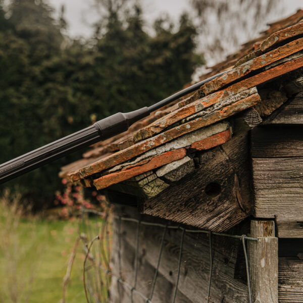 Close up of flexible end tube directed under roof tiles during treatment